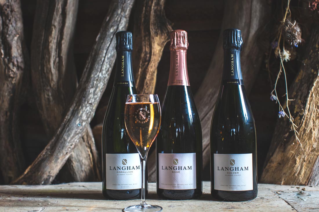 Three bottles and a wine glass of sparkling wine from Langham Wine Estate in Dorset