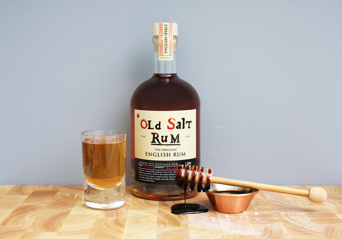 Bottle of Old Salt Rum with shot glass and molasses