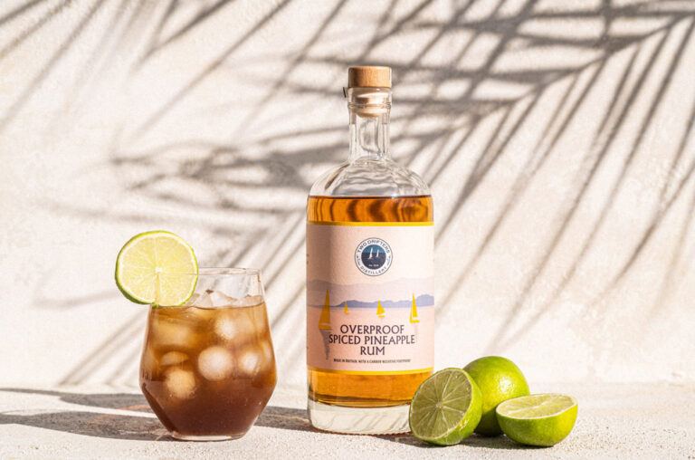 Bottle of Two Drifters pineapple rum with glass and limes