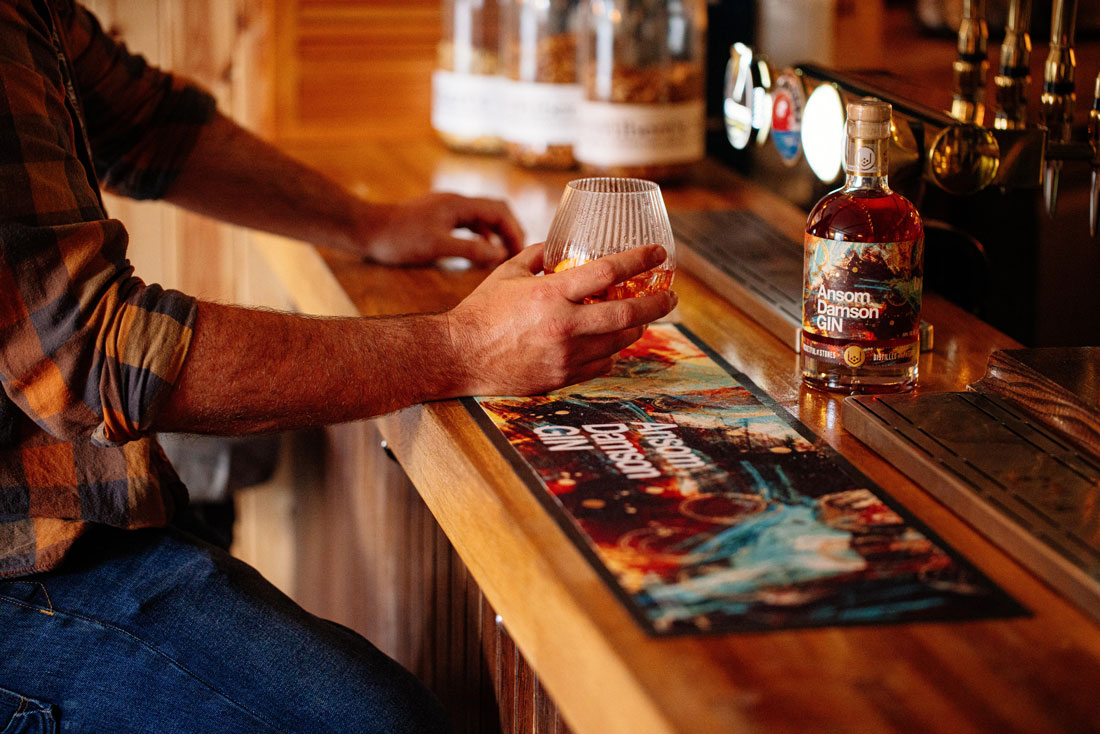 Man drinking Ansom Damson Gin at a bar. Christmas spirits